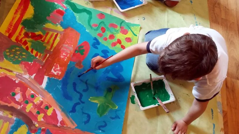 Gyerekek közösen festenek egy nagy papírra a földön
